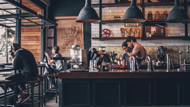 A café with a rustic interior, wooden tables, and hanging pendant lights.