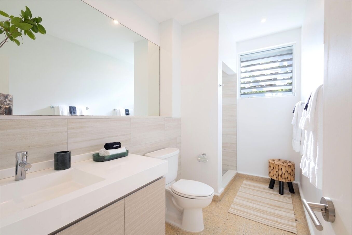 Une salle de bain moderne avec un grand miroir, un lavabo, des toilettes et un espace douche.