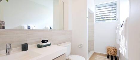 Une salle de bain moderne avec un grand miroir, un lavabo, des toilettes et un espace douche.