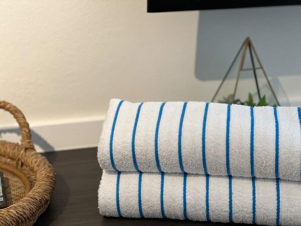 A folded white towel with blue stripes on a dark wooden surface.