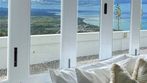 A room with large windows offering a view of a coastal landscape.
