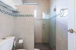 Une salle de bain avec une douche à parois de verre, des toilettes et un lavabo.