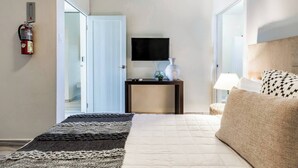 A hotel room with a bed, bedside table, lamp, and a flat-screen TV.