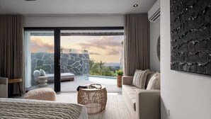 Un dormitorio moderno con un amplio ventanal corredera que da a una zona de piscina, un sofá, una cama y un adorno en la pared.