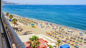 A beach with rows of sun loungers and umbrellas, a lifeguard tower, and a clear view of the sea. - Capitan by Interhome (Fuengirola)