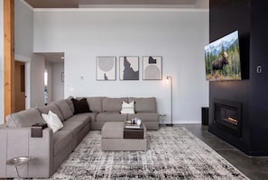 A modern living room with a sectional sofa, a fireplace, and three framed artworks on the wall.