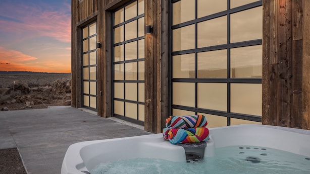 Un jacuzzi con una toalla colorida, frente a un edificio con ventanas amplias y vistas a un paisaje desértico.