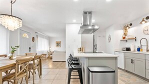 Una cocina moderna con una isla central, electrodomésticos de acero inoxidable y una araña.