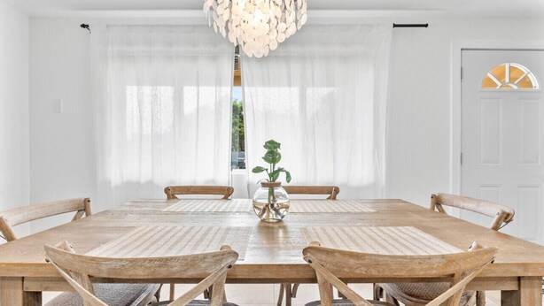 Comedor con mesa y sillas de madera, un florero con planta y una araña.