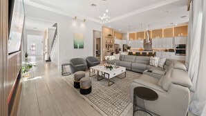 Een moderne woonkamer met een bank, fauteuils, een salontafel en een trap die naar een ander niveau leidt.