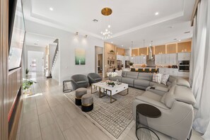 Ein modernes Wohnzimmer mit einer Couch, Sesseln, einem Couchtisch und einer Treppe, die zu einer weiteren Ebene fĂŒhrt.
