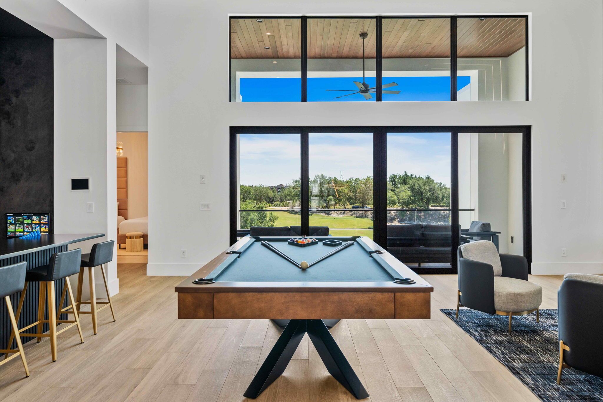 A modern indoor pool table with a view of a green landscape through large windows.