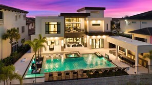 A modern two-story house with a swimming pool, outdoor seating, and a well-lit interior. - The Luxe Escape-TT474 (Kissimmee)