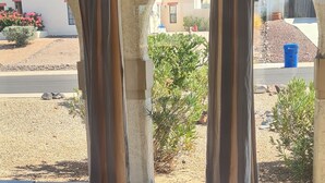 A room with a large window, a red chair, and a striped rug. - Calm saguaro cacti house with palms and oleanders, chirping quails.  (Phoenix)