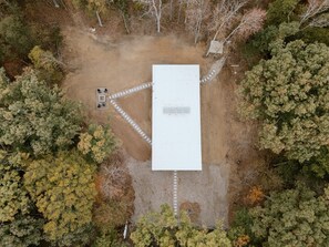 An aerial view of a rectangular building with a paved driveway leading to a gated entrance.