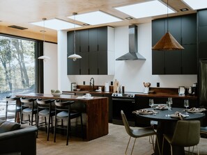A modern kitchen with dark cabinetry, a central island, and pendant lighting.