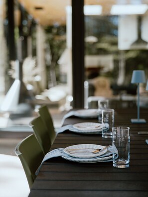 A dining table set with plates, glasses, and cutlery, with chairs around it.