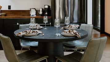 A modern dining area with a round table, six chairs, and a central light fixture.