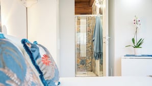 Et soveværelse med en seng, en bruser med glasdør, en plante og en vægmonteret lampe.