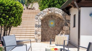 A stone archway leading to a patio area with outdoor seating and a fruit bowl. - Villa Agave - Superior Spa Room (Gaggi)