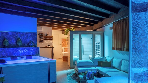 A modern living room with a sofa, a coffee table, and a kitchen area with a counter and shelves. - Villa Agave - Superior Spa Room (Gaggi)