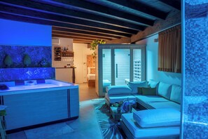 A modern living room with a sofa, a coffee table, and a kitchen area with a counter and shelves.