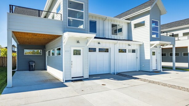 Une maison moderne à deux étages, dotée d’un garage, d’un patio couvert et d’une cour arrière clôturée.
