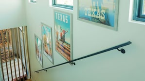 Portaat, joissa on puiset askelmat ja metallinen kaide, johtavat ylätasanteelle, jossa on suuret ikkunat ja kehyksiin asetetut julisteet, joissa esiintyy Texasin maisemia.