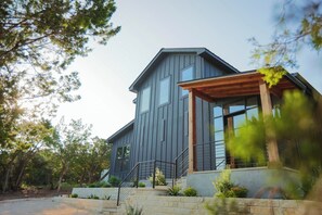 Una casa moderna a due piani con fondamenta in pietra, ampie finestre e un portico in legno.