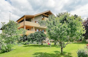 A multi-story building with balconies, surrounded by a well-maintained garden.