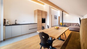 A modern kitchen with wooden cabinets, a dining table, and a sofa in a living area. - Apartment 'Linderhof Cima' with Mountain View, Shared Pool and Wi-Fi (Natz)