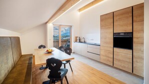 A modern kitchen with wooden cabinets, a dining table, and heart-shaped chairs. - Apartment 'Linderhof Cima' with Mountain View, Shared Pool and Wi-Fi (Natz)