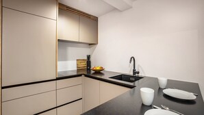 Una cocina moderna con encimera negra, un fregadero y un bol de fruta.