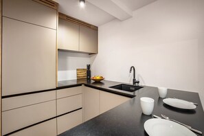 Una cocina moderna con encimera negra, un fregadero y un bol de fruta.
