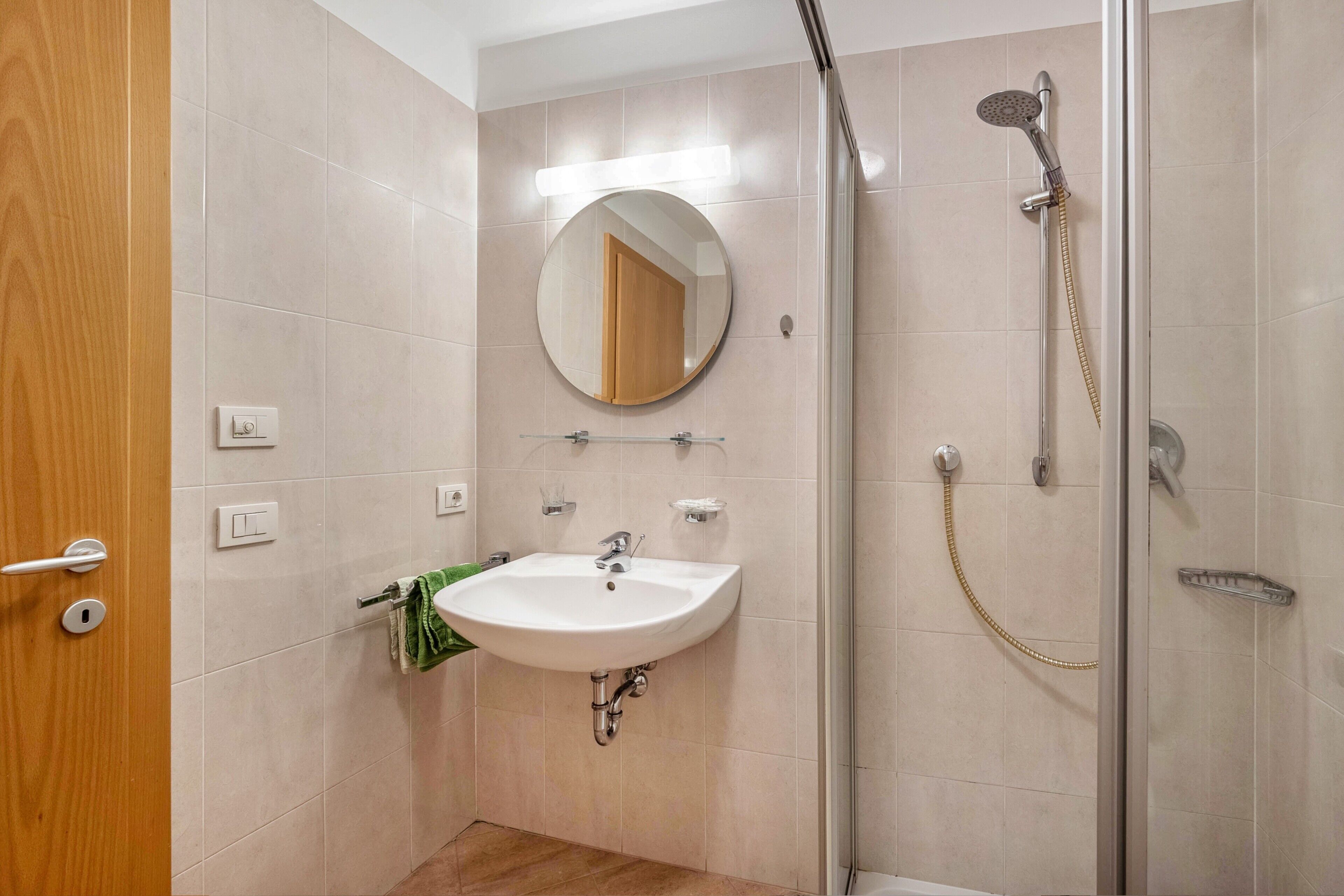Une salle de bain avec un lavabo, un miroir, une douche et une porte en bois.
