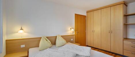 Ein Schlafzimmer mit einem Bett, Nachttischen, einem Kleiderschrank und Wandlampen.