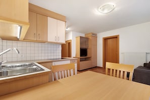Une cuisine avec des meubles de rangement en bois, un évier et une table à manger avec des chaises.