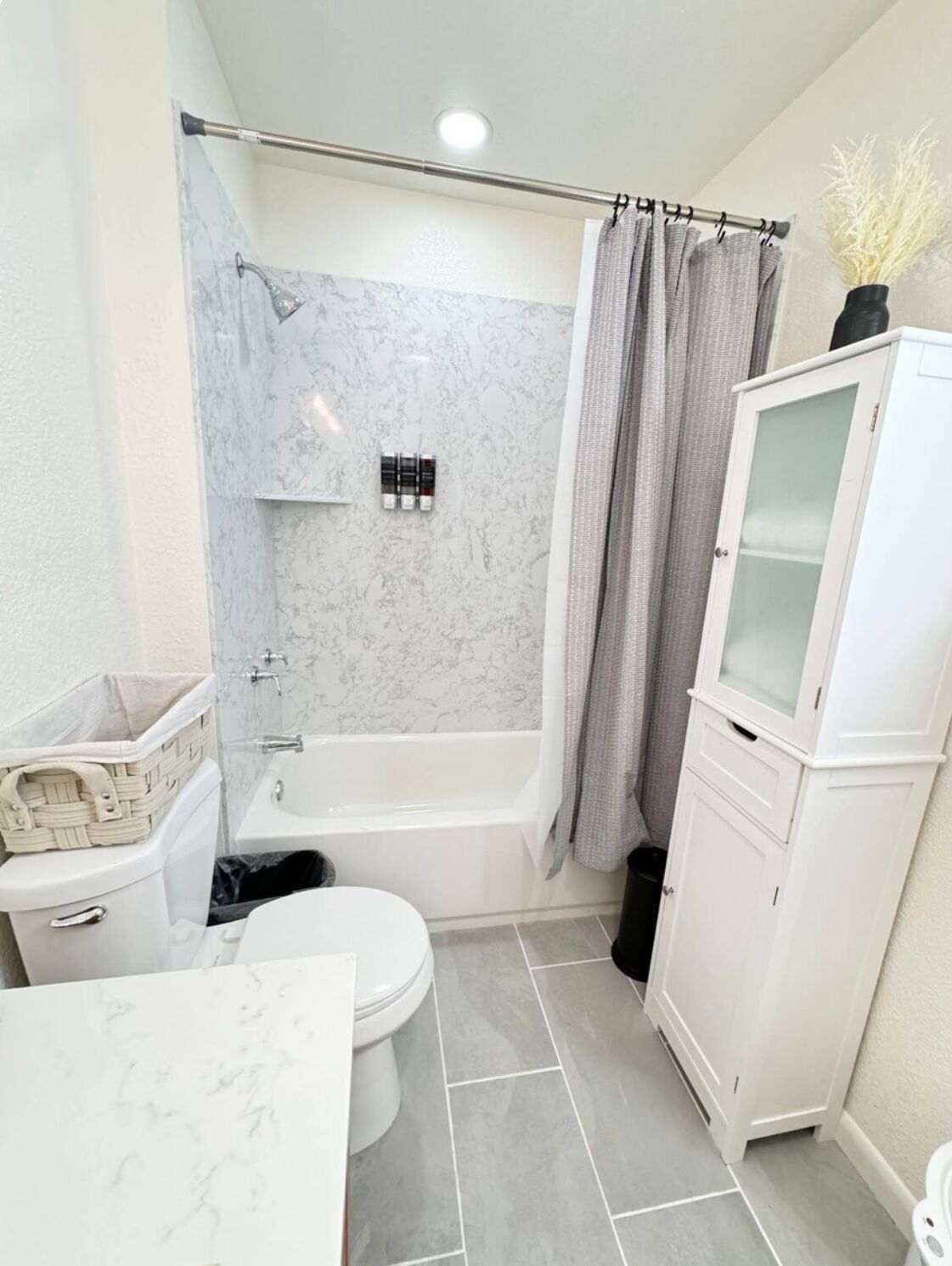 A bathroom with a toilet, bathtub, shower, and a cabinet.
