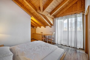 Une chambre avec un plafond en bois, un lit, un bureau et des chaises.