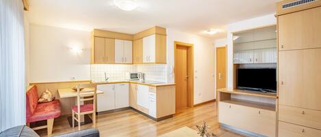 A compact living space with a kitchenette, a dining area, a sofa, and a TV.