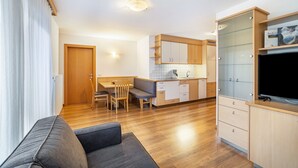 A modern kitchen with wooden cabinets, a dining area with a bench, and a television on a cabinet. - Apartment 'Linder 20' with Mountain View, Shared Pool and Wi-Fi (Natz)