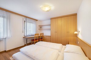 Une chambre avec deux lits, un bureau avec une chaise, une armoire et un radiateur.