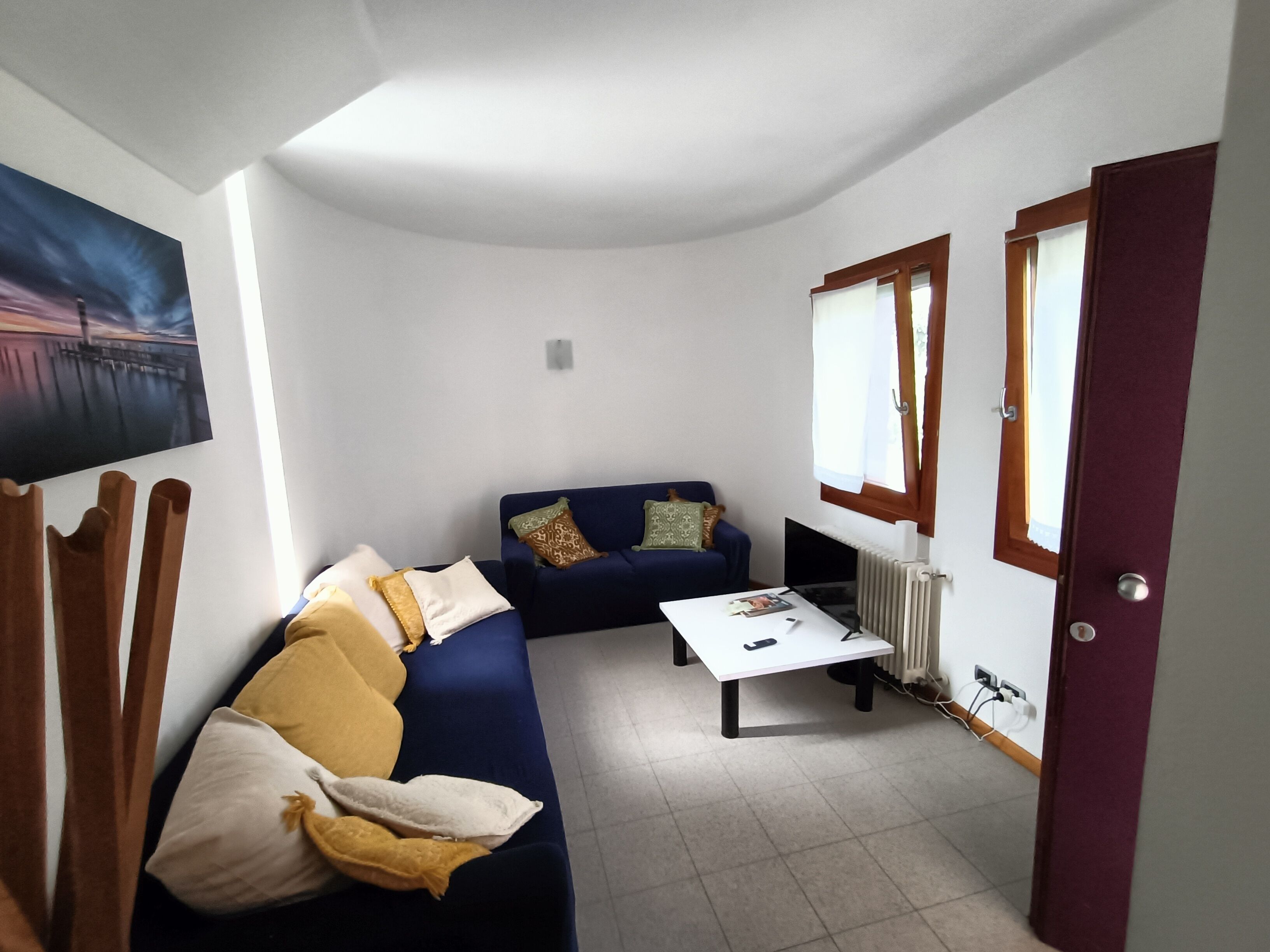 A compact living space with a sofa, a coffee table, and a painting on the wall.