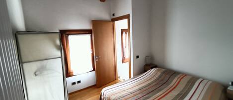 Un dormitorio con una cama, un armario y una puerta que da a otra habitación.
