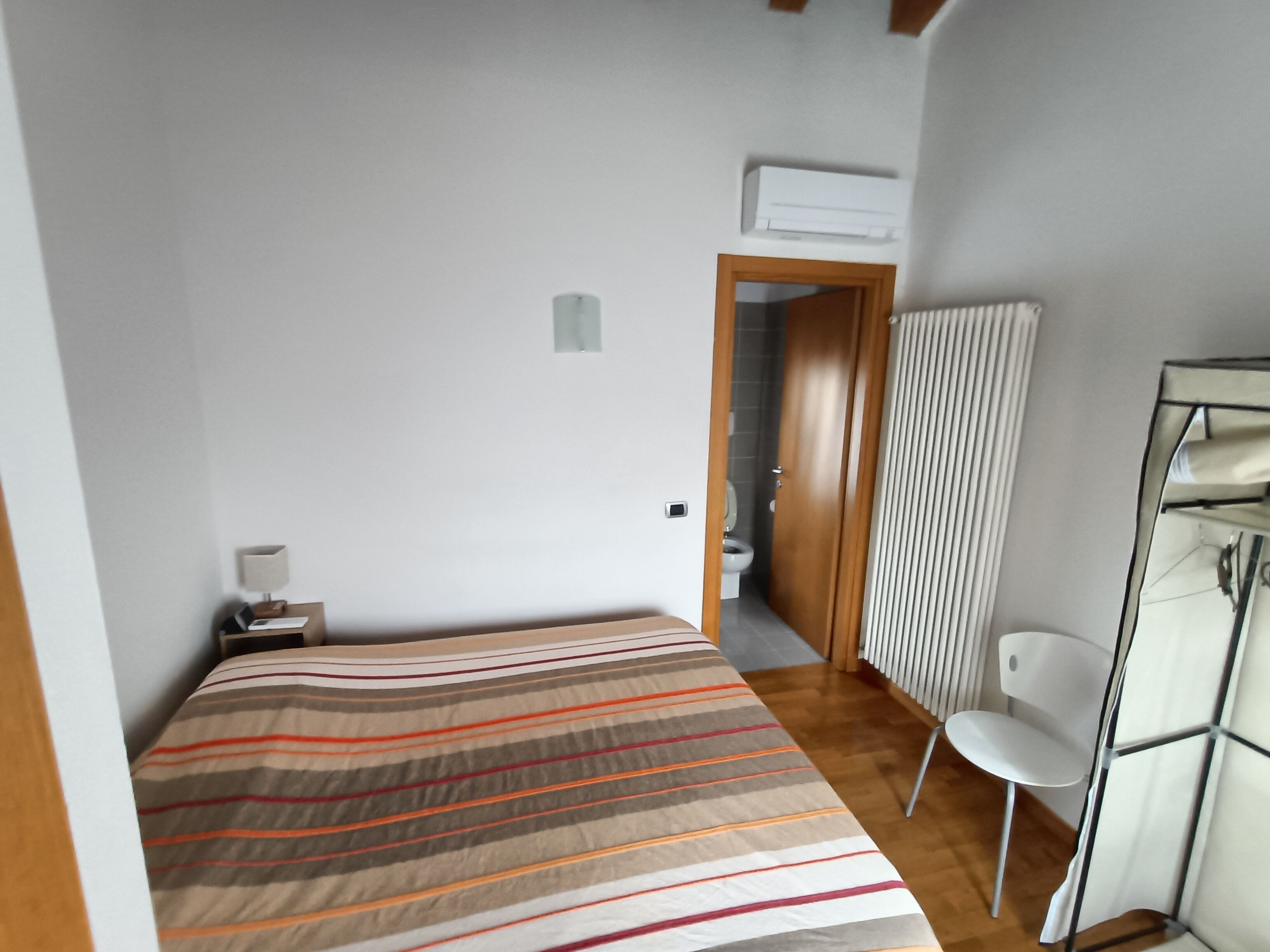 Ein Schlafzimmer mit Bett, Stuhl, Nachttisch und einer Tür zu einem Badezimmer.