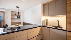 Een moderne keuken met een zwart aanrecht, inbouwkeukens, een spoelbak en een koffiezetapparaat.