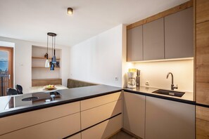 Eine moderne Küche mit schwarzem Arbeitsplatz, eingebauten Schränken, einer Spüle und einer Kaffeemaschine.