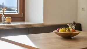 A wooden bowl on a table with fruits, a window, and a vase with flowers. - Apartment 'Linderhof Panorama Terrasse' with Mountain View, Shared Pool and Wi-Fi (Natz)