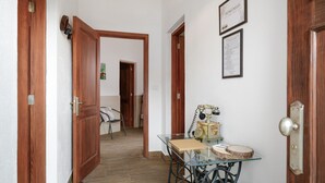 A hallway with wooden doors, a glass table with a vintage telephone, and a welcome sign.
