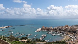 Une ville côtière dotée d’un port de plaisance, de bâtiments historiques et d’un ciel dégagé.
